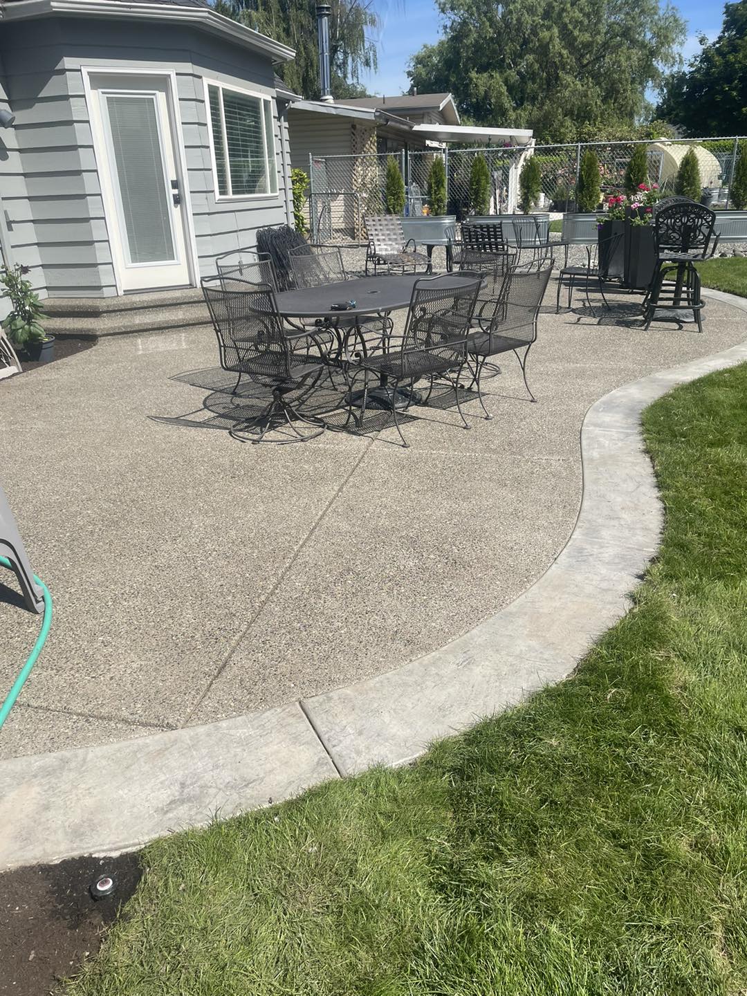 Exposed aggregate concrete patio with stamped border and outdoor furniture